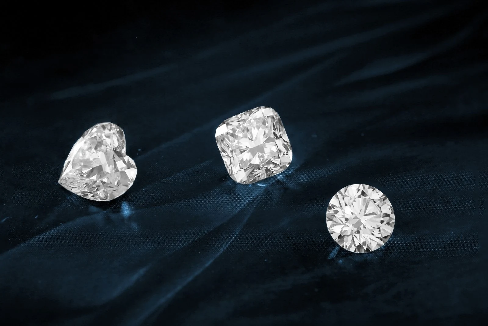 Three diamonds in heart, cushion and round cuts displayed side by side