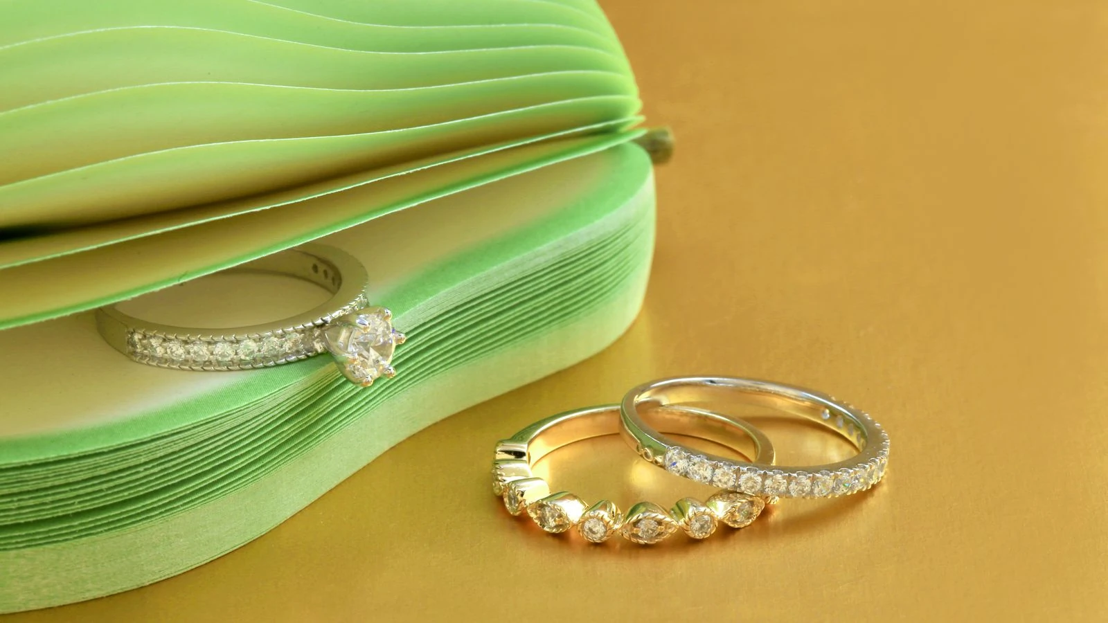 Several diamond rings in different shapes displayed on a gold surface