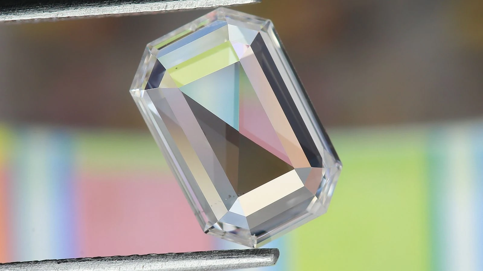 Emerald cut diamond held by tweezers, showing its elongated outline
