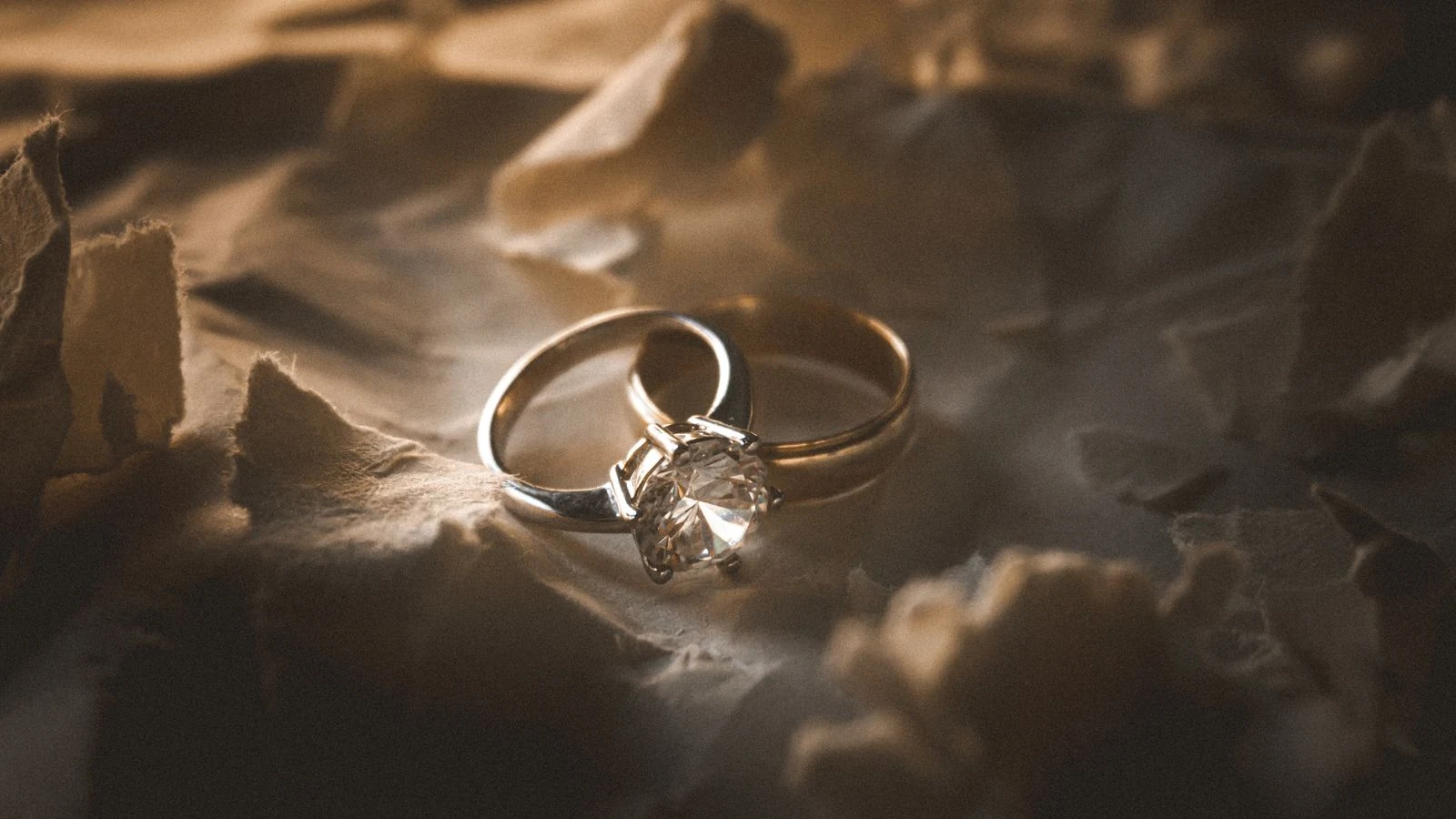 Diamond and gold rings arranged on a textured surface